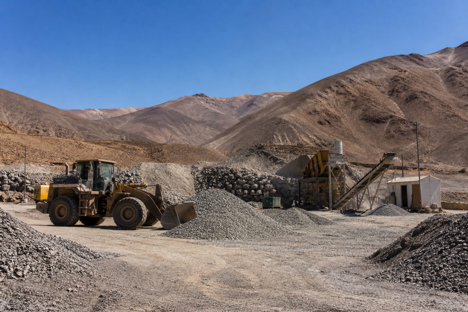 Medium-sized mining operation with loader, crushing equipment and mineral stockpiles