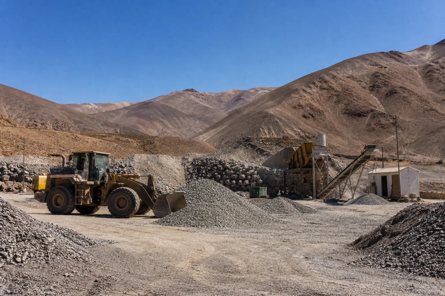 Medium-sized mining operation with loader, crushing equipment and mineral stockpiles
